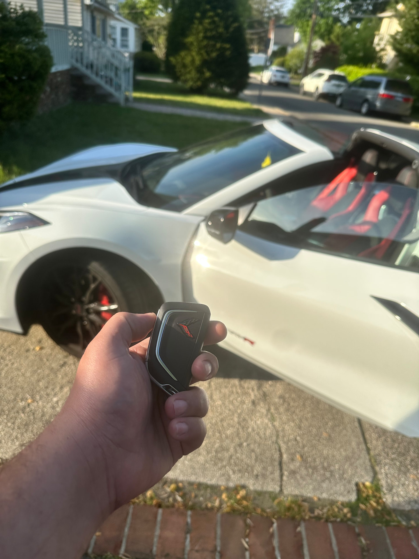 Freshly programmed Chevrolet Corvette key fob held in front of the car in a Nassau County driveway